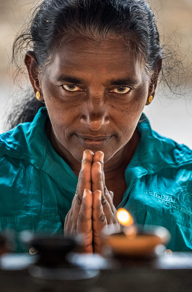 In Sri Lanka, at the Temple of the Tooth Relic, a pilgrim prays at entrance to temple